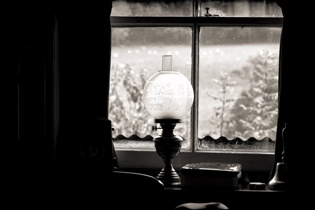 Antique oil lamp with etched globe shade on window sill