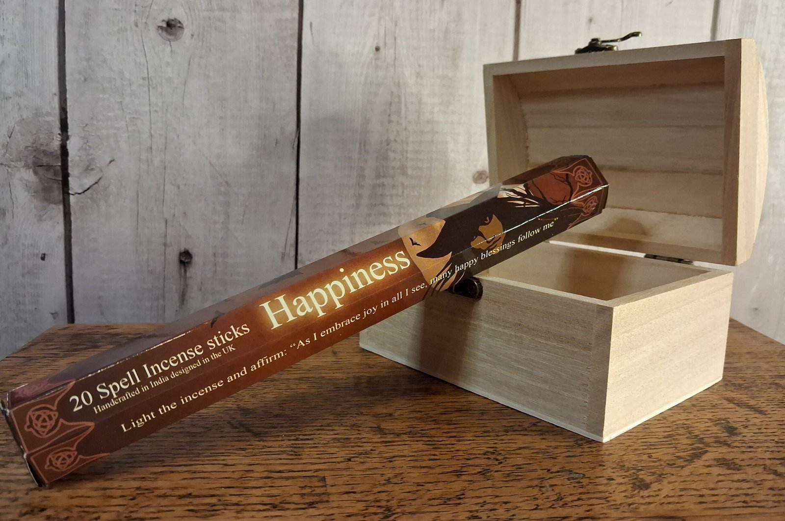 Elements Happiness Spell Incense Sticks by Lisa Parker 1 A tube of incense sticks with package designed by Lisa Parker. Package is brown, black and cream with face of a witch in front of a full moon and bare tree