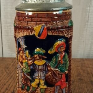 A stein of ceramic and pewter depicting 3 muscians, one kissing a barmaid while his fellow musician stabs him